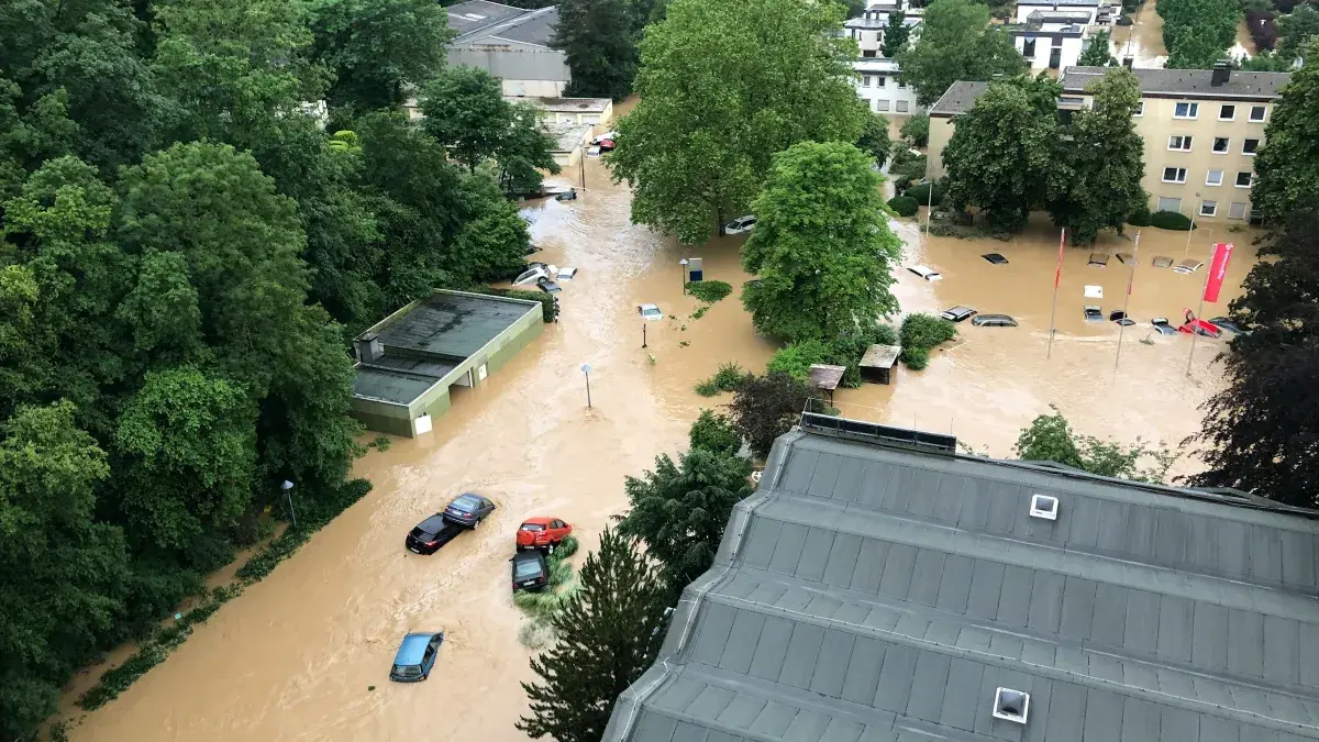 An aerial photo of a flash flood, cars and houses are submerged in the murky water