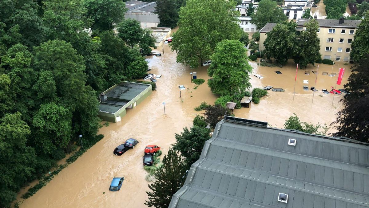 An aerial photo of a flash flood, cars and houses are submerged in the murky water