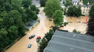 An aerial photo of a flash flood, cars and houses are submerged in the murky water
