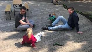 David sits with his friend and colleague Adrien as they play with their daughters