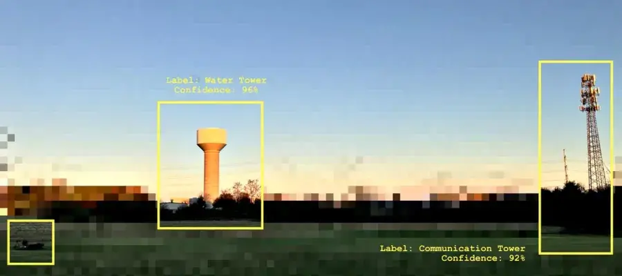 The image features a pixelated landscape with a stretch of grass. There is a water tower in the middle and a communication tower to the right. The image also features a small sun in teh sky and a cow/sheep. These features are all outlined in yellow boxes with percentages indicating the image recognition confidence.