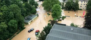 An aerial photo of a flash flood, cars and houses are submerged in the murky water