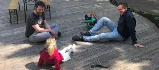 David sits with his friend and colleague Adrien as they play with their daughters