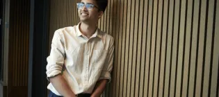 Adi Kumar leans against a pannelled wall