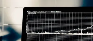 Photo of a laptop screen in a lab. It is dark and displays graphs of health data.