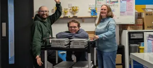 Rayo and Rosie posing with a trolley stacked with laptops in Eagle Labs