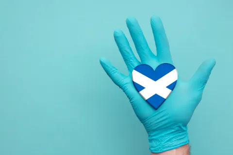 Hand with medical gloves and Scottish flag shaped as a heart