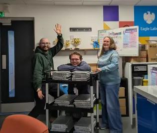 Rayo and Rosie posing with a trolley stacked with laptops in Eagle Labs