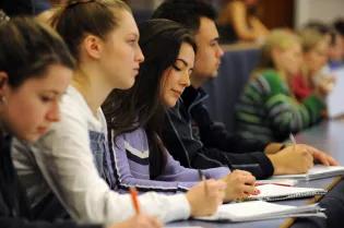 A row of students sat taking notes in a lecture